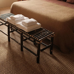 Banc de bout de lit en bois brûlé Bosc Design avec serviettes pliées, chambre aux tons naturels