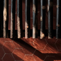 Rondins de bois brûlé du banc Bosc Design sur tomettes hexagonales en terre cuite